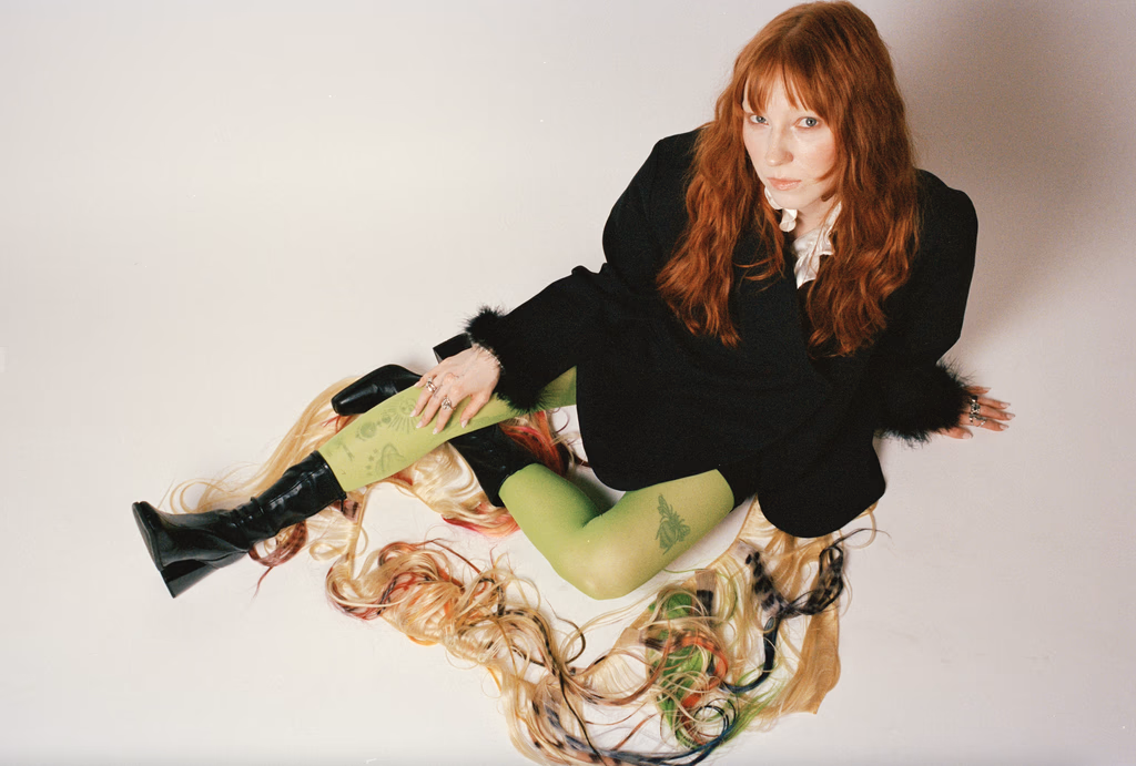 Linny in schwarzem Outfit mit langen Haaren und grünen Strümpfen